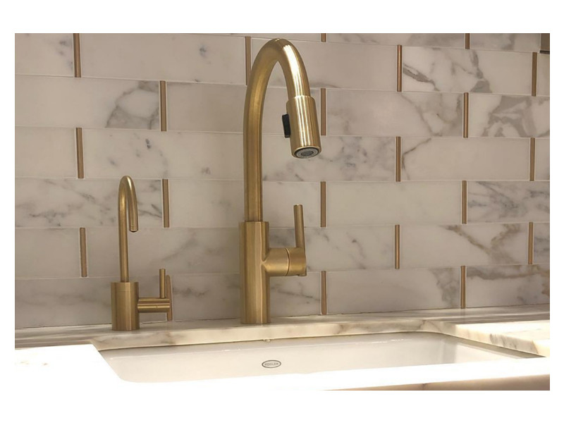 A detailed view of the Love of Brass marble mosaic backsplash, made from Calacatta Gold and matte brass accents.