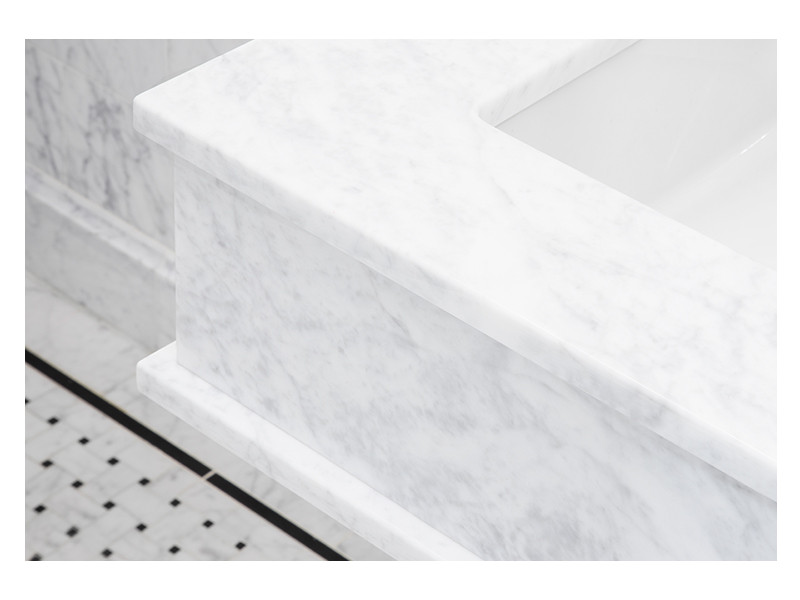 A detailed view of the custom fabricated vanity made from Carrara Claro Light marble. 