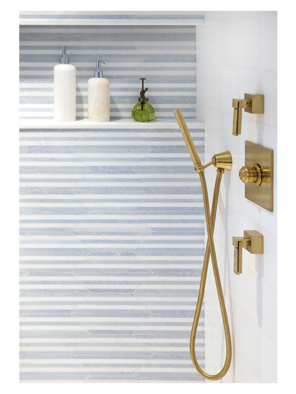 A close up of Jordan Hilton's beautiful guest bathroom shower wall, featuring the Art of Deco Streamline Moderne Azul mosaic from the Complete Tile Collection on the walls, made from polished Thassos and Blue Celeste marble.
