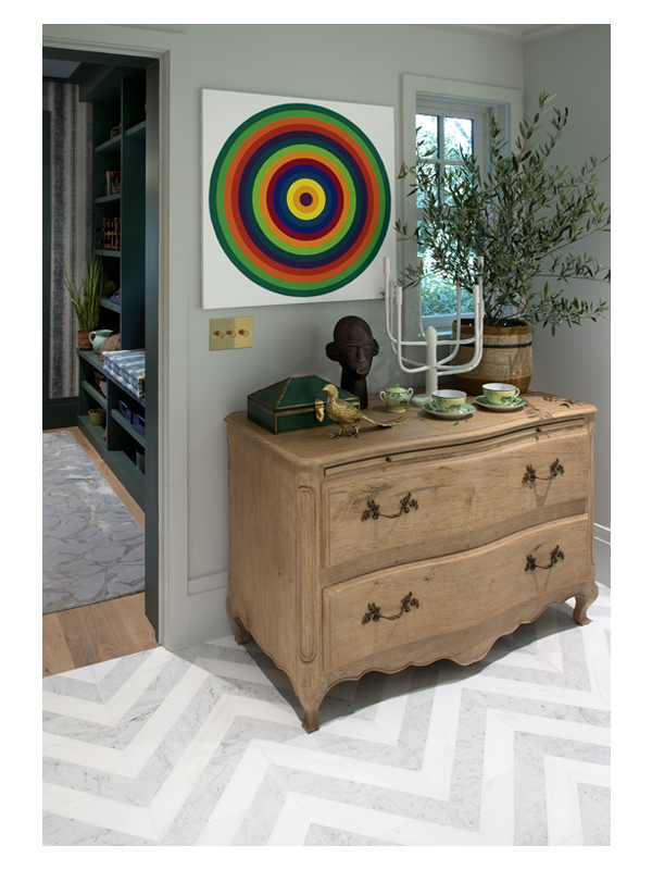 Eclectic art and a grand wooden chest highlight the Art of Deco Chevron Solid floor tile from the Complete Tile Collection. It is made from White Whisp Dolomiti and Carrara Claro Light honed marble. 