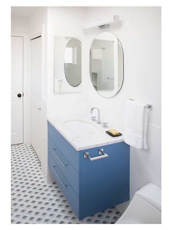 The blue custom floating vanity in this guest bathroom design by Karen Blankenship Interiors. The Venice marble mosaic by the Complete Tile Collection is installed on the floor.
