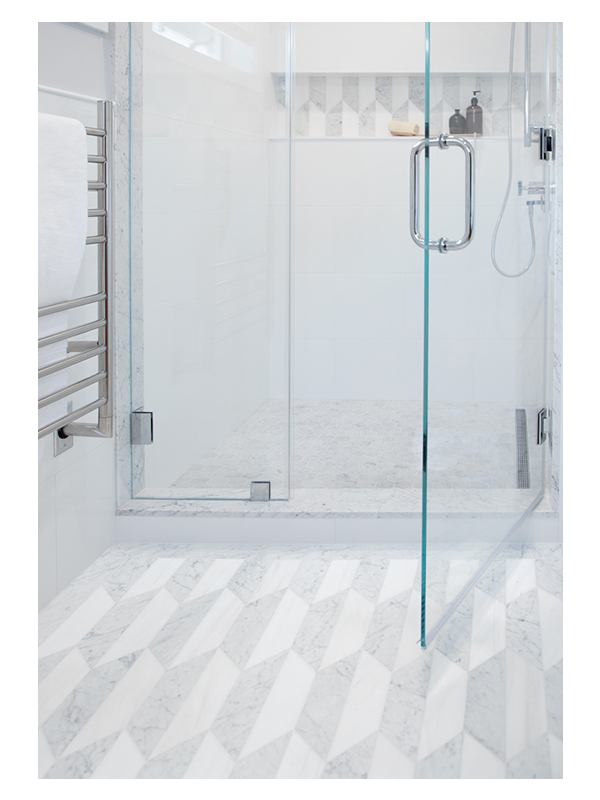 A detailed shot of the master bathroom shower area, featuring the Art of Deco Chrysler Spire Solid pattern, made from White Whisp Dolomiti and Carrara Claro Light honed marble.